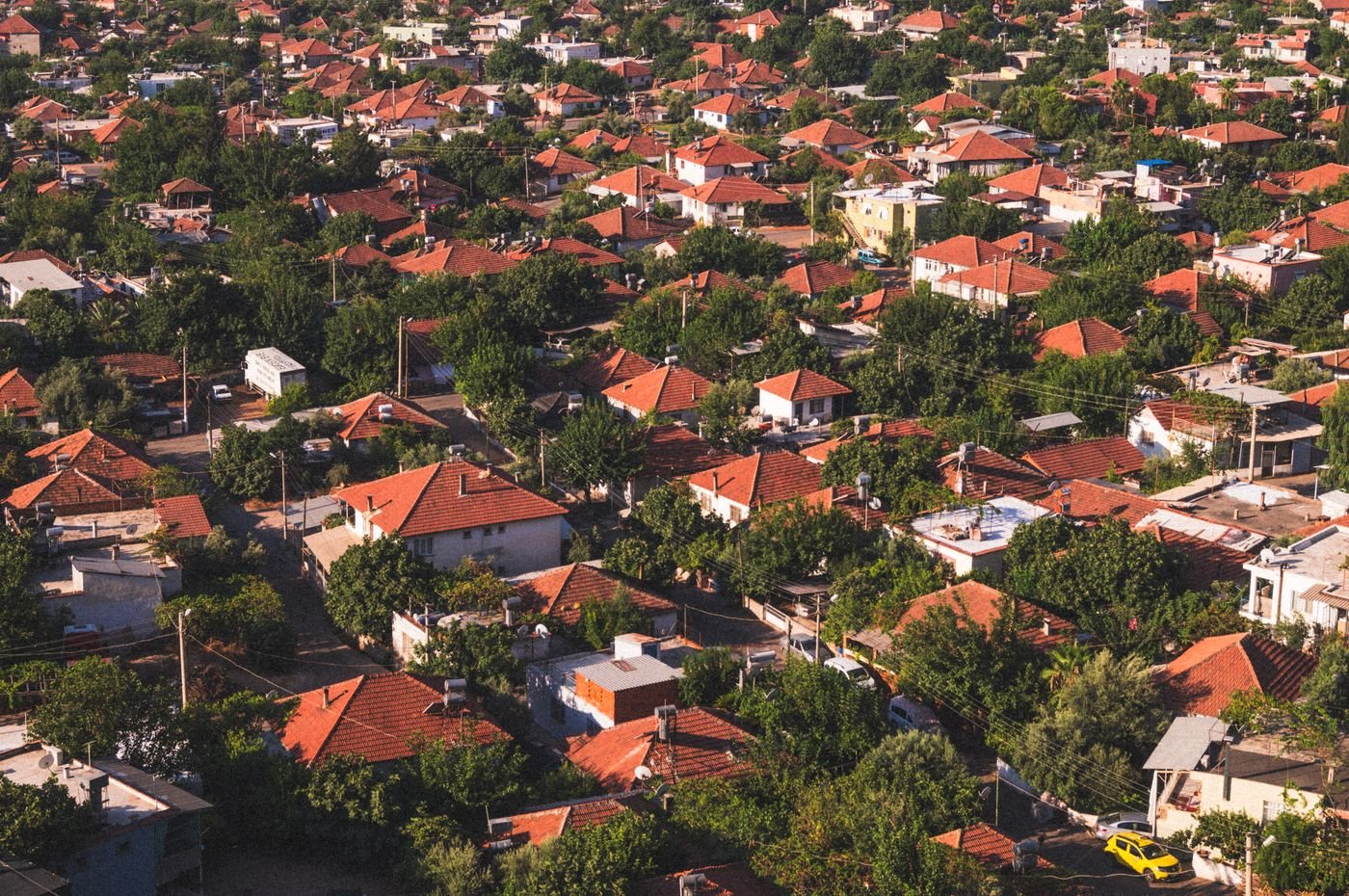 Door hanger delivery in Missoula, MT Vibrant aerial view of a suburban neighborhood with red-tiled roofs surrounded by lush greenery.