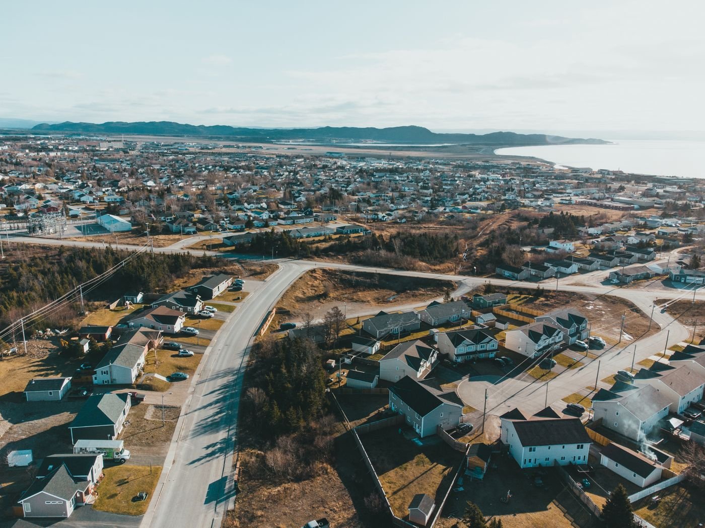 Door hanger delivery in Sioux City, IA Drone view of coastal settlement with small houses and asphalt road near sea and mountain on background under light blue sky on sunny day in autumn