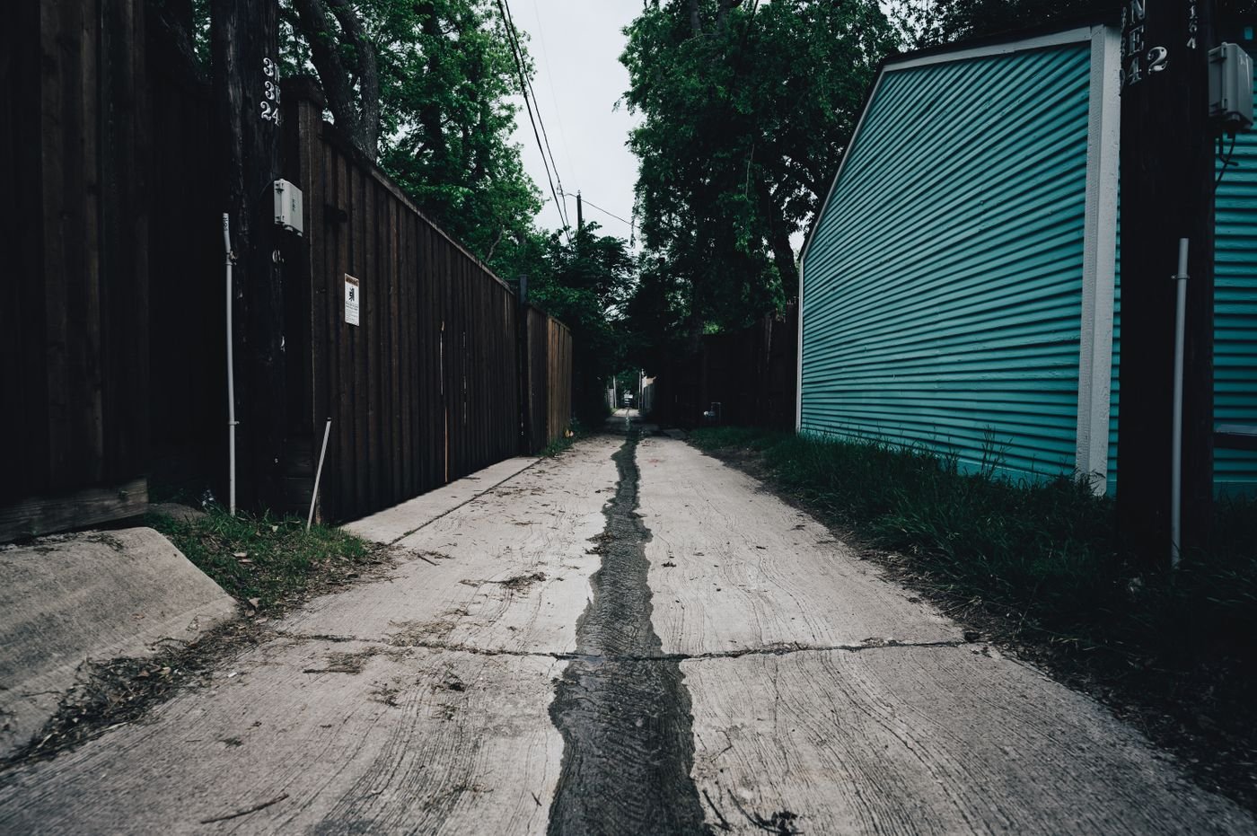 Door hanger delivery in Medford, OR Empty narrow alleyway with a wooden fence and grass, offering a moody atmosphere.